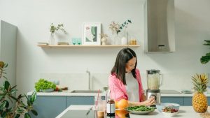 A woman blends fresh ingredients for a healthy smoothie in a stylish kitchen, promoting wellness.